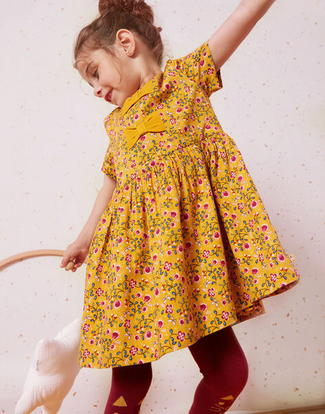 petite fille avec une robe jaune à motifs qui joue 